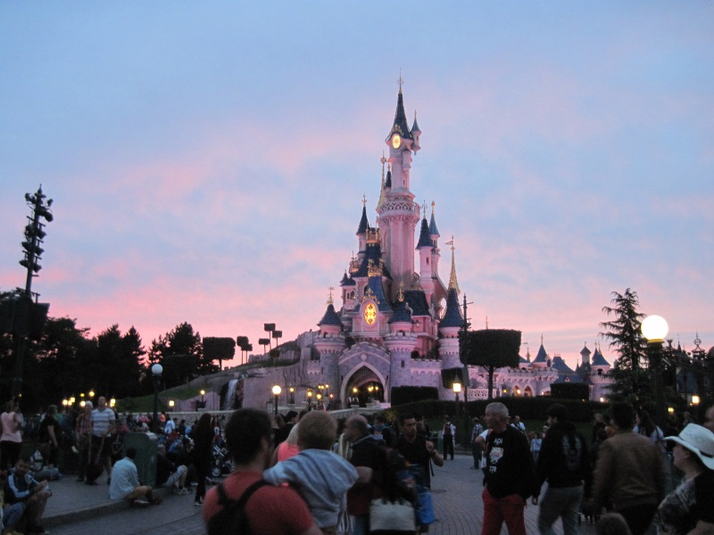 Sleeping Beauty Castle in Fantasyland, Disneyland Park, Paris, at sunset as visitors await the Disney Illuminations show.