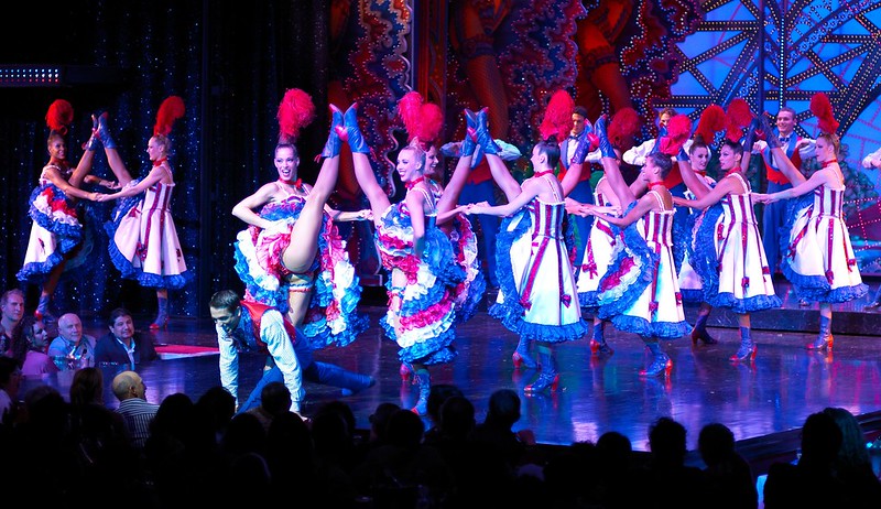 Young ladies in colorful costumes perform Cancan dance on the stage of the famous Moulin Rouge cabaret in Montmartre, Paris.