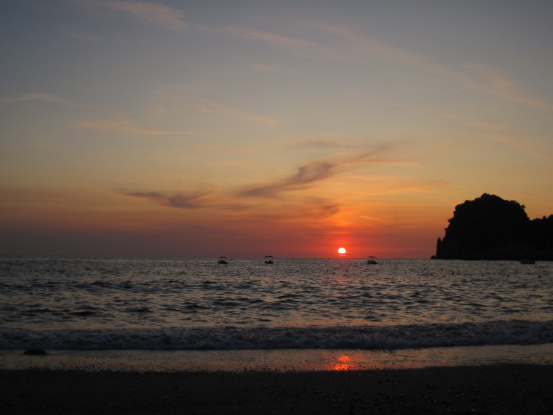 A view of the sun going down below the horizon of the Ionian Sea from Ermones Beach on the west coast of Corfu Island. 