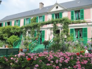 Home of Claude Monet in Giverny, Normandy, teeming with flower beds and trees in the garden and ivy covering windows.
