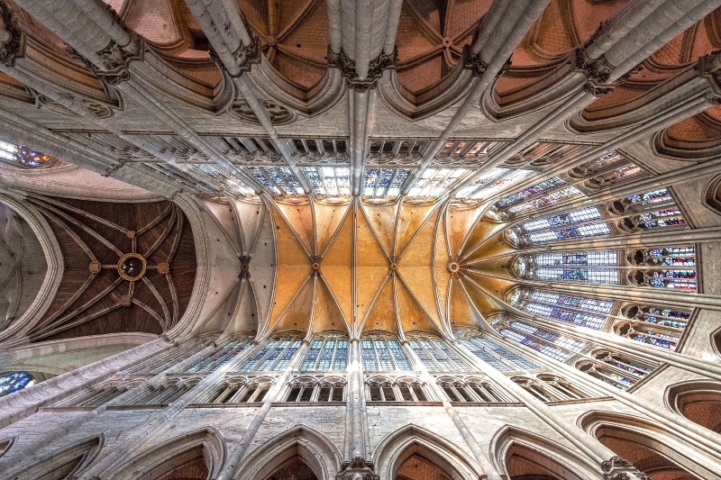 High rib vault, stained-glass windows, and pillars of Saint-Pierre Cathedral in Beauvais, France, seen from the ground level.