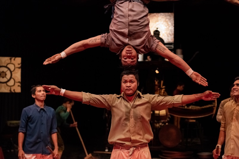 An artist of Phare, the Cambodian Circus performs a headstand on another performer's head during the White Gold show.