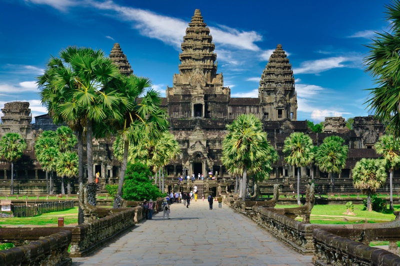 Angkor Wat Temple, featuring five towers and palms lining the path to its entrance, is a stunning sight on a clear day.