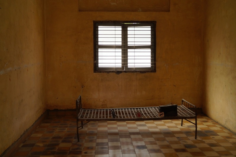 The sinister look of an S-21 prison cell (Tuol Sleng Museum of Genocide) with grating on the window and a metal bed.