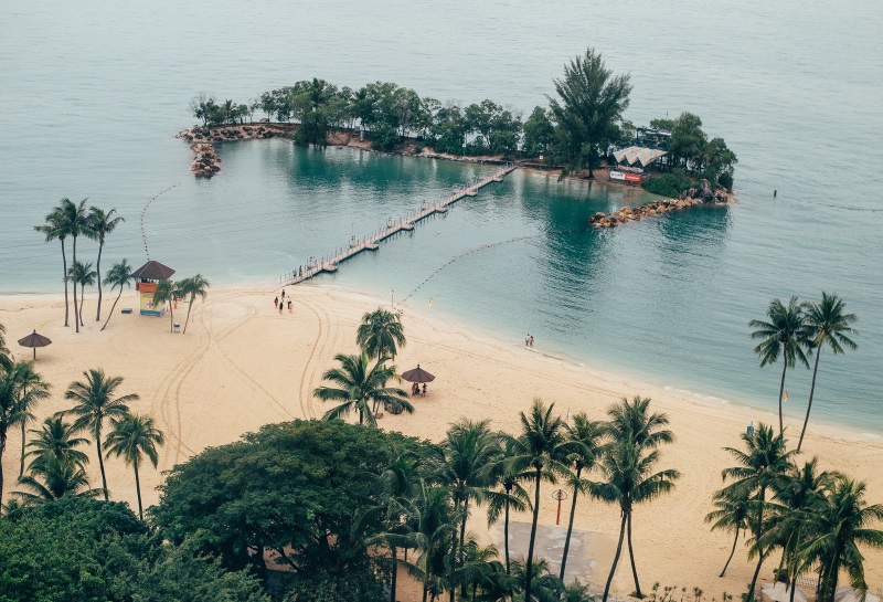 View of popular Siloso Beach on Sentosa Island, Singapore, from the zipline reveals a bridge leading to the nearby islet.