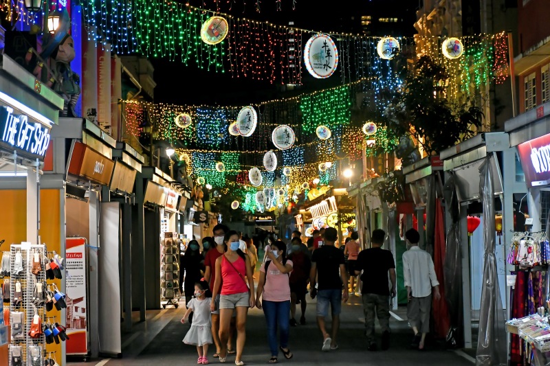 A shopping street in Singapore Chinatown brims with stores selling various goods, eager shopaholics, and sightseers at night.